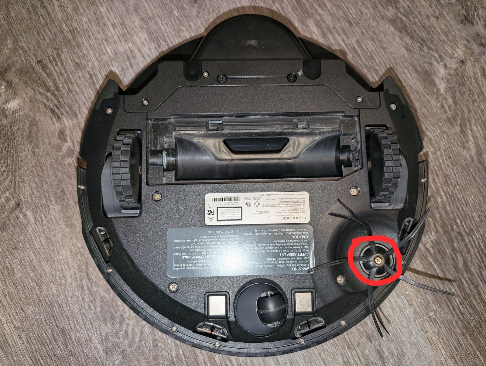 The single screw holding the side brush is circled in red.